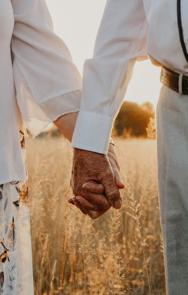 Elderly couple holding hands: Love as a practice, not a promise.